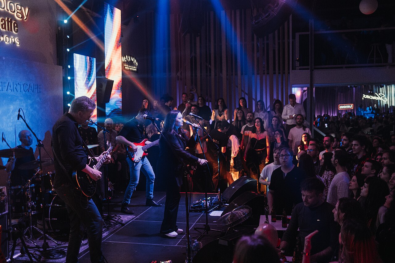 A musician performing on stage with dynamic lighting, making eye contact with the audience.